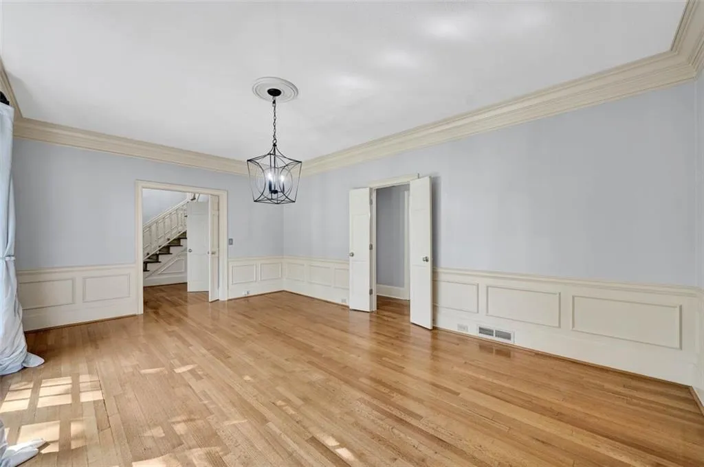 Unfurnished dining area with a notable chandelier, ornamental molding, and light wood-type flooring