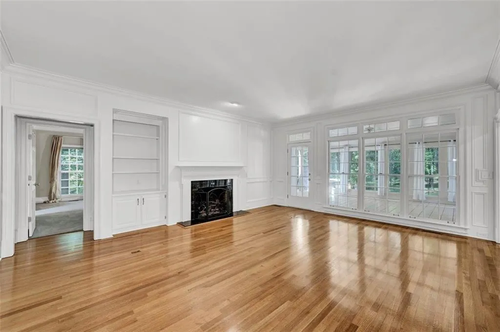 Unfurnished living room with crown molding, a fireplace, built in features, and light hardwood / wood-style flooring