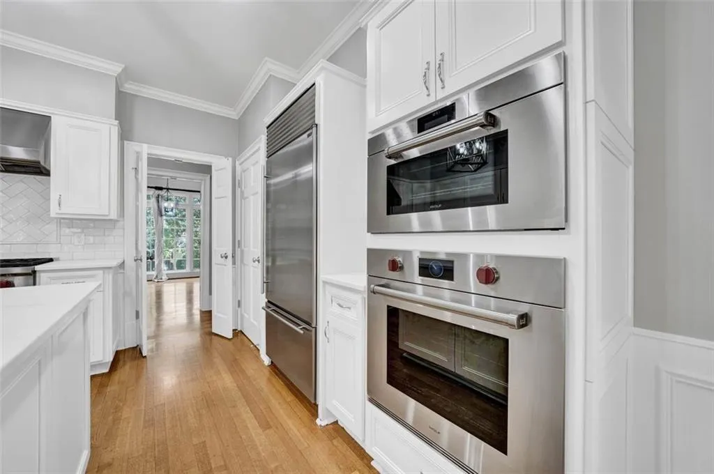 Kitchen with stainless steel appliances, white cabinets, tasteful backsplash, and light wood-type flooring