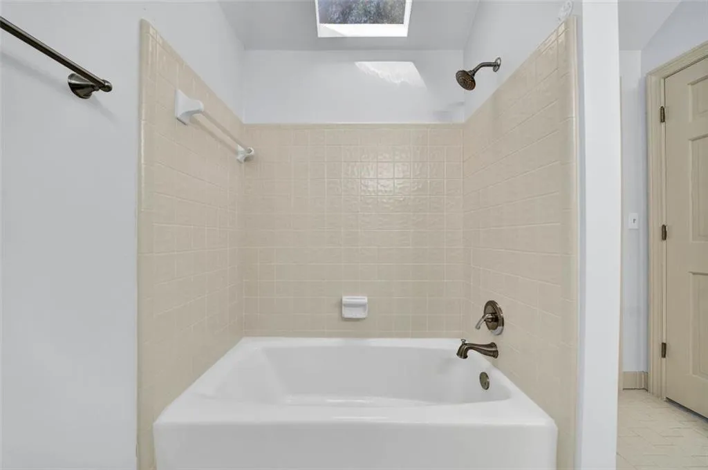 Bathroom featuring tile flooring, a skylight, and tiled shower / bath