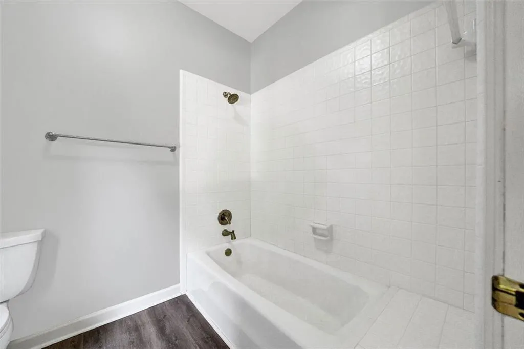Bathroom featuring wood-type flooring, toilet, and tiled shower / bath combo