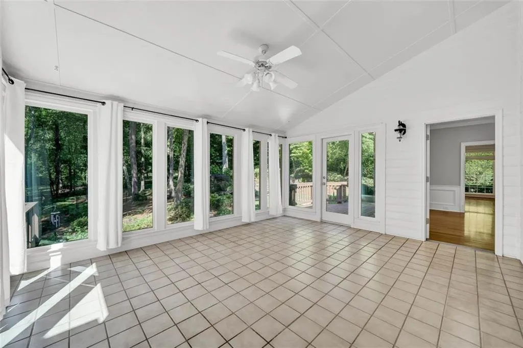 Unfurnished sunroom with ceiling fan and vaulted ceiling