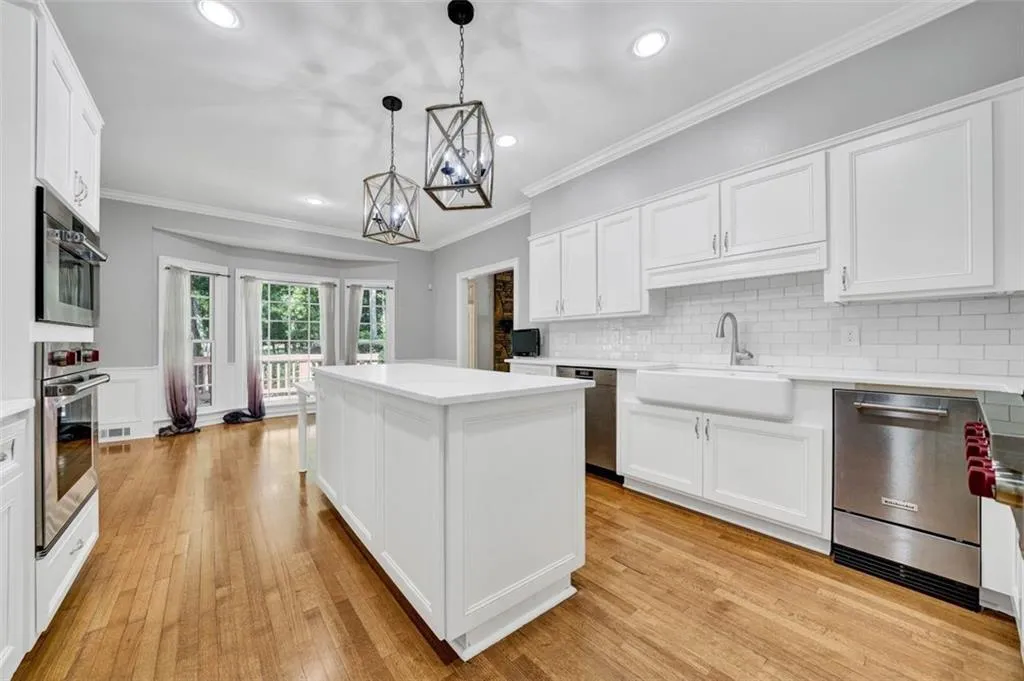 Kitchen featuring a center island, light hardwood / wood-style floors, stainless steel appliances, sink, and tasteful backsplash