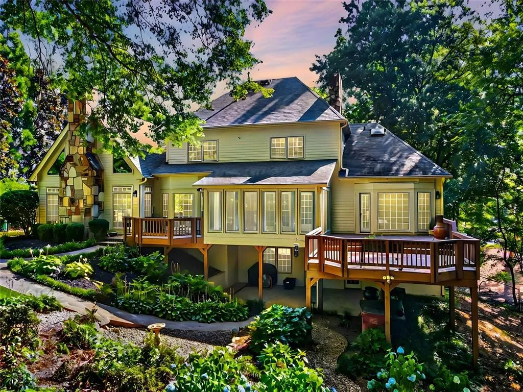 Back house at dusk with a wooden deck and a sunroom