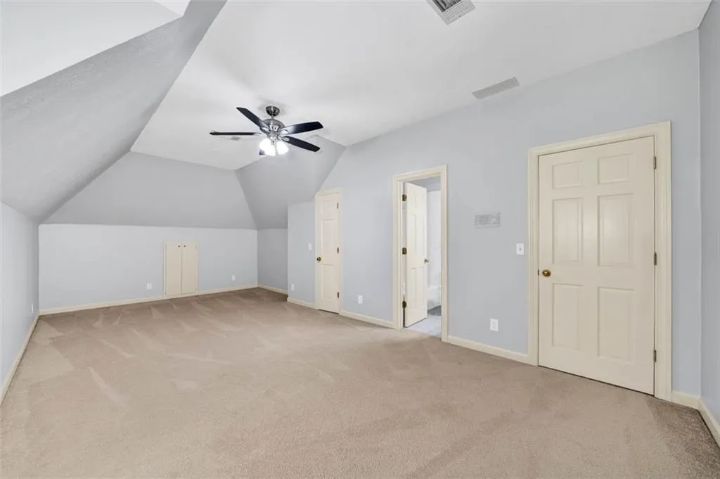 Bonus room with ceiling fan, vaulted ceiling, and light colored carpet