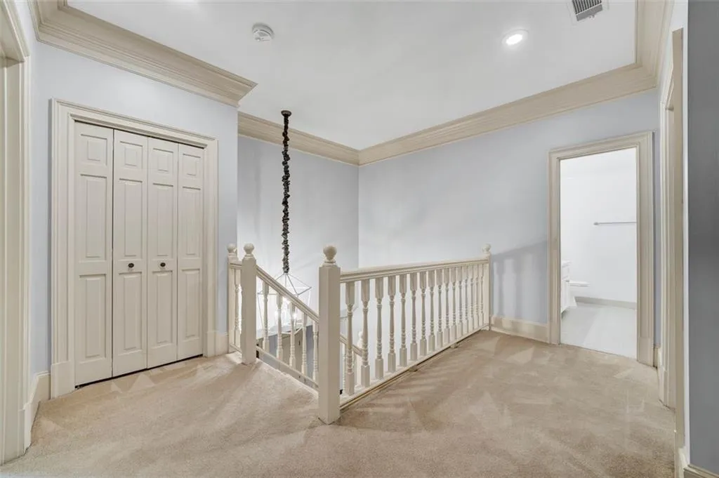 Hall with crown molding and light carpet
