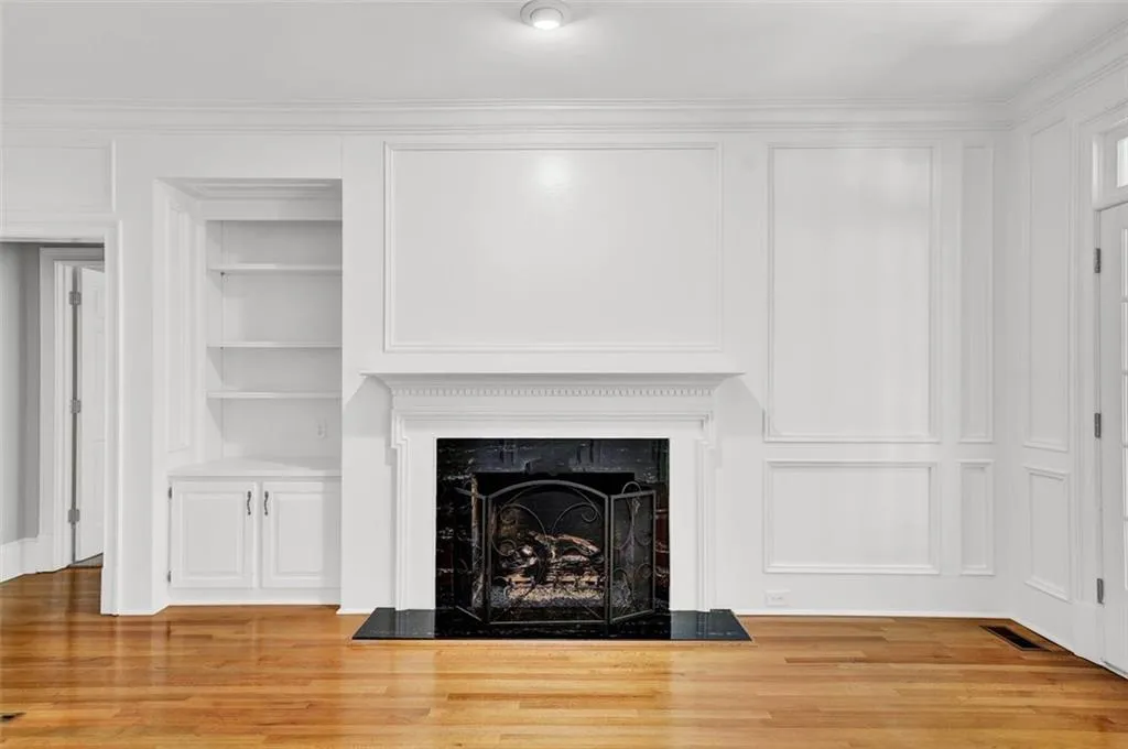 Unfurnished living room featuring crown molding, built in shelves, and light hardwood / wood-style flooring