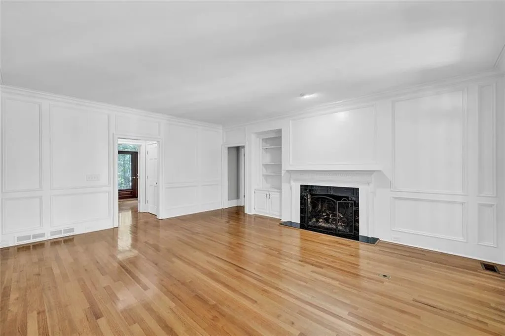 Unfurnished living room featuring light hardwood / wood-style floors, ornamental molding, built in features, and a high end fireplace