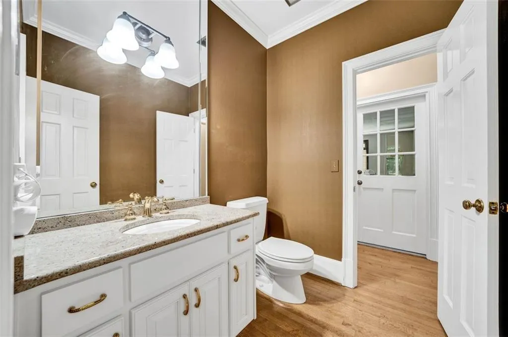 Bathroom with ornamental molding, hardwood / wood-style flooring, toilet, and vanity