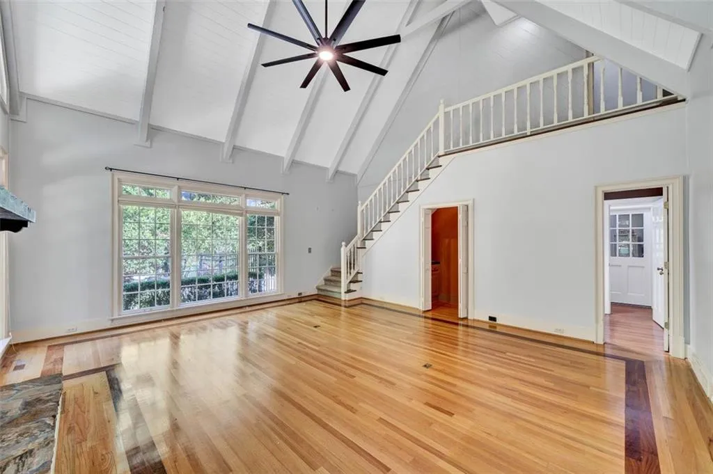 Unfurnished living room featuring beam ceiling, high vaulted ceiling, and wood-type flooring