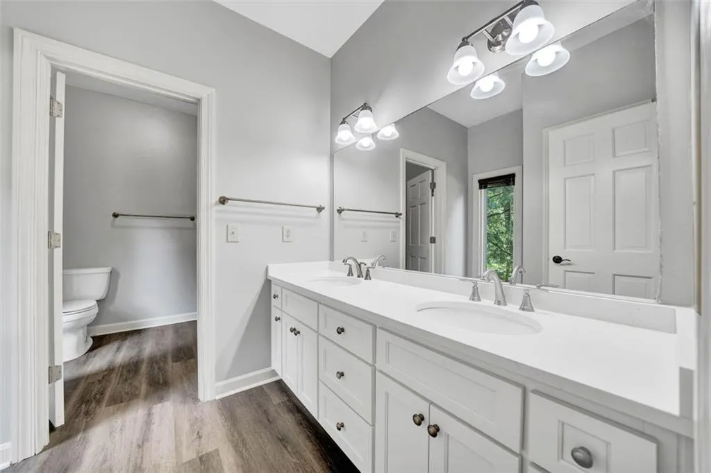 Bathroom with double vanity, hardwood / wood-style flooring, and toilet