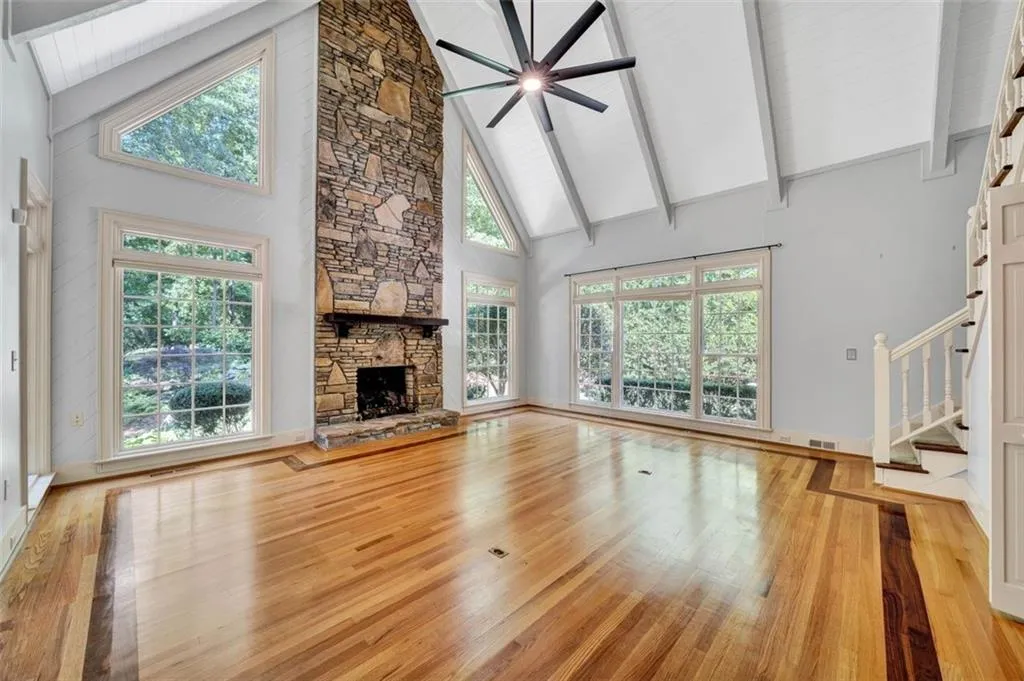 Unfurnished living room with high vaulted ceiling, a healthy amount of sunlight, a fireplace, and wood-type flooring