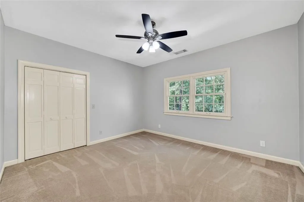 Unfurnished bedroom featuring carpet, ceiling fan, and a closet