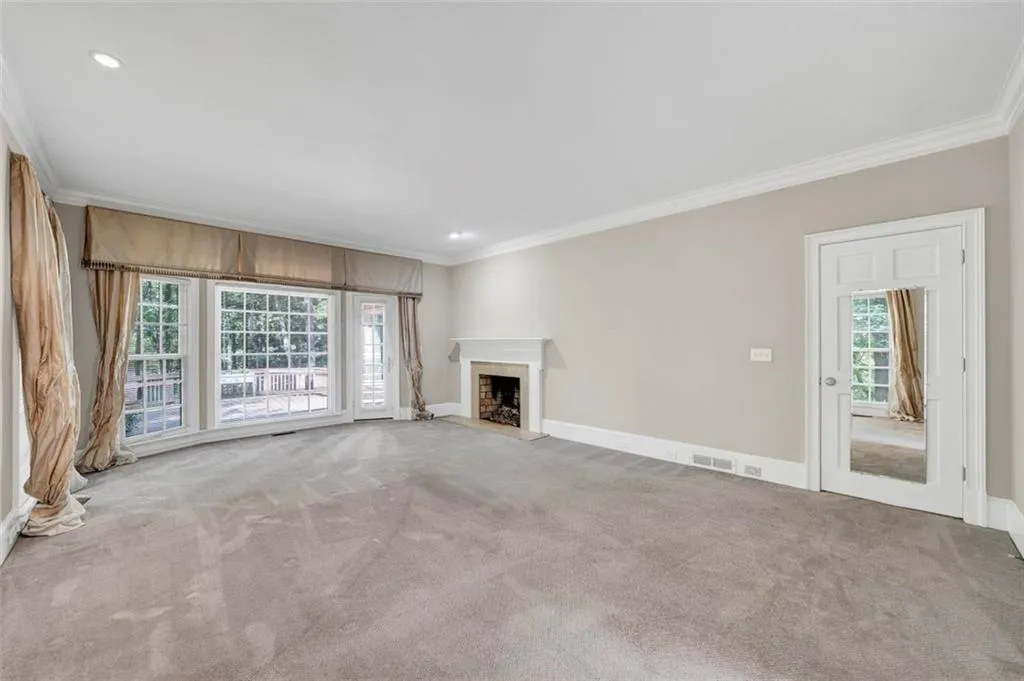 Unfurnished living room featuring ornamental molding, carpet floors, and a wealth of natural light