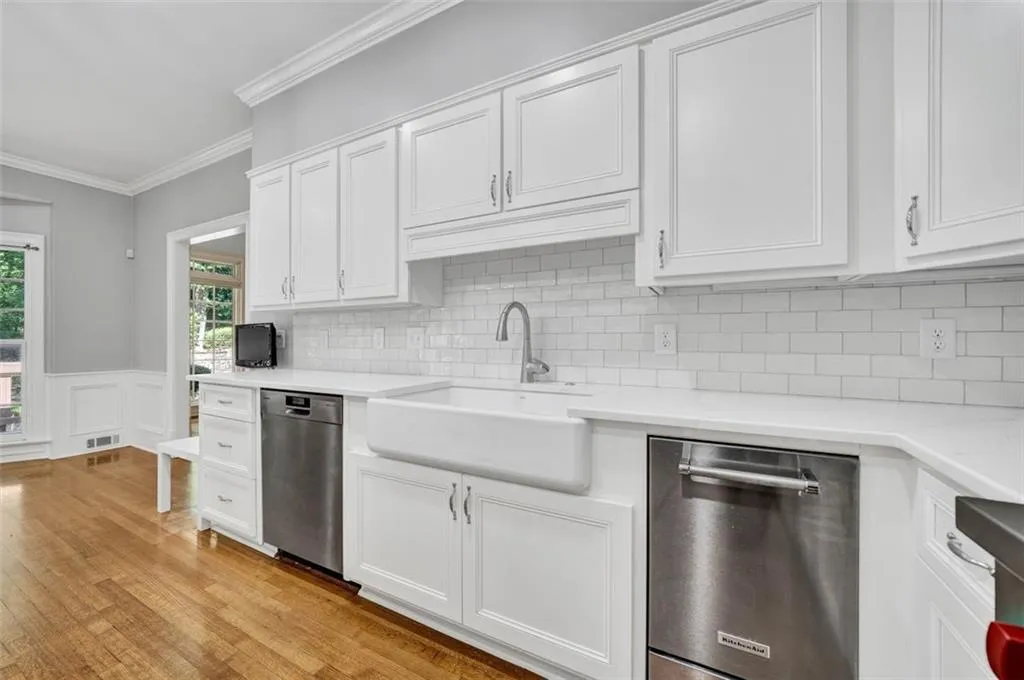 Kitchen featuring white cabinets, stainless steel dishwasher, and light hardwood / wood-style flooring