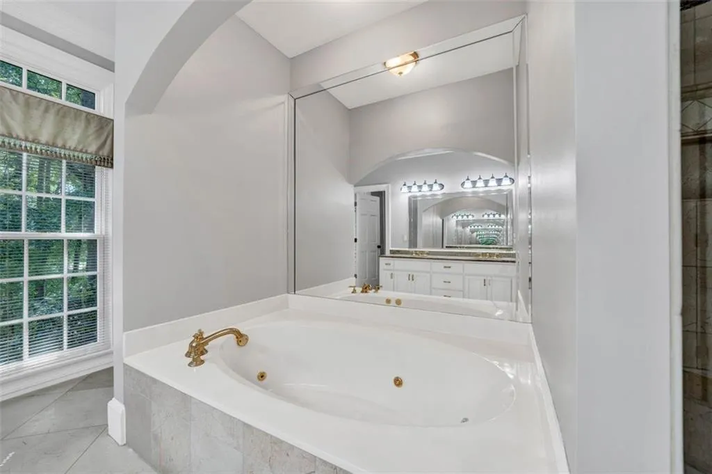 Bathroom featuring tiled bath, vanity, and tile floors