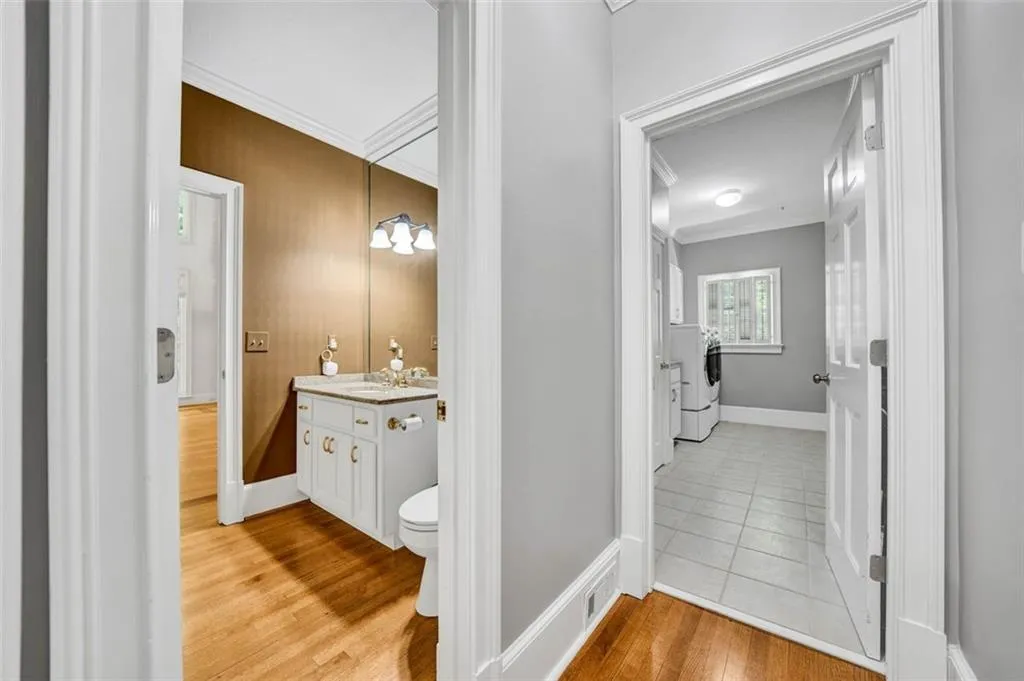 Bathroom featuring separate washer and dryer, tile flooring, ornamental molding, vanity, and toilet