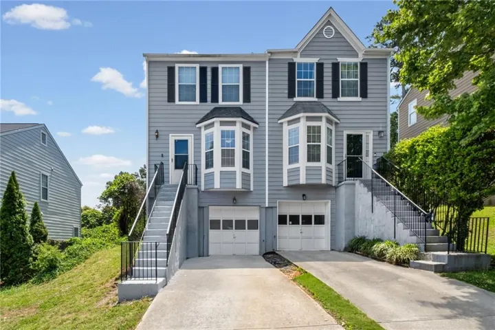Modern two-story residence featuring a distinctive curved bay window design, horizontal siding exterior, and a two-car garage with paneled doors