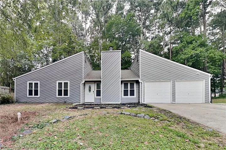 Contemporary exterior with a unique roofline, gray horizontal siding, and a prominent chimney feature