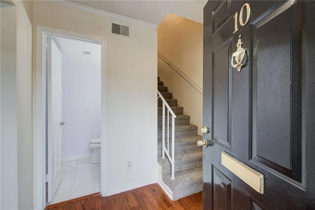 Staircase with ornamental molding and wood finished floors