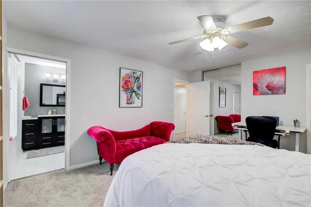 Bedroom featuring carpet floors, ensuite bathroom, an office area, a ceiling fan, and a closet
