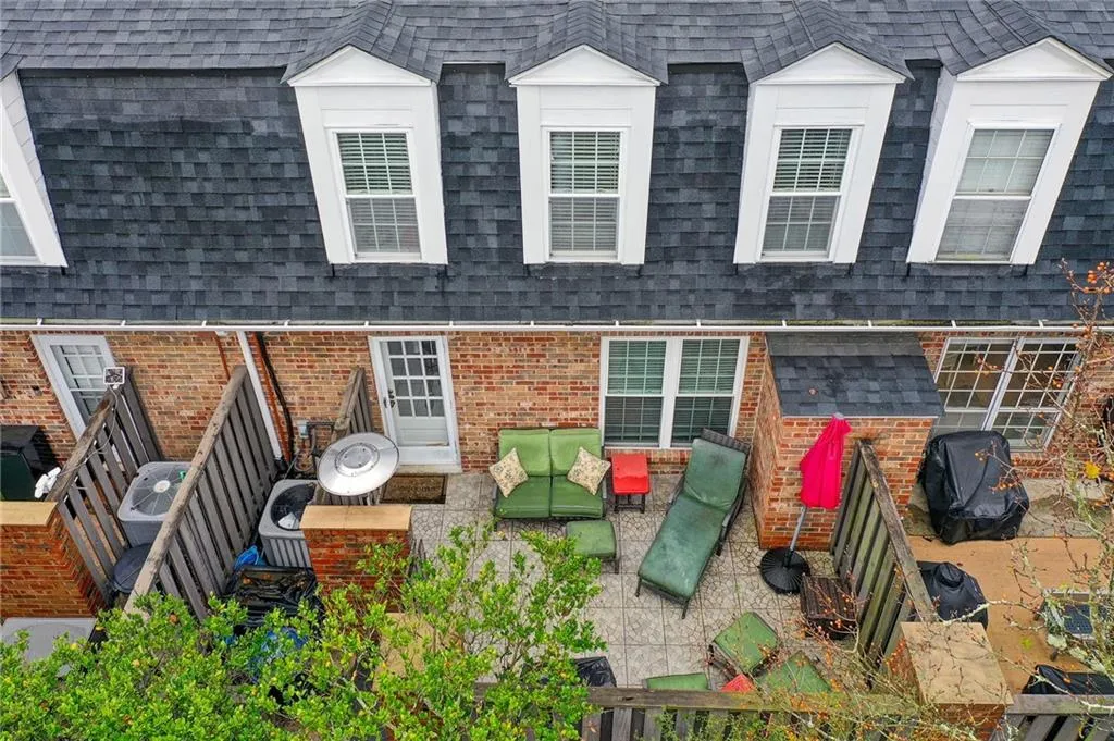 Back of property with a patio, brick siding, roof with shingles, and an outdoor hangout area
