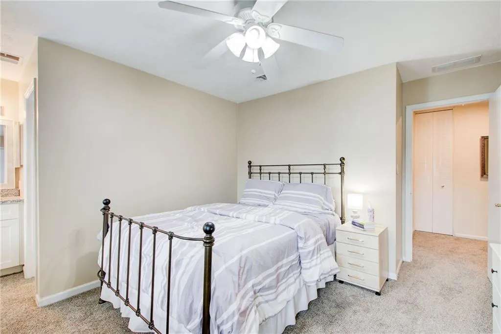 Bedroom with light colored carpet and a ceiling fan