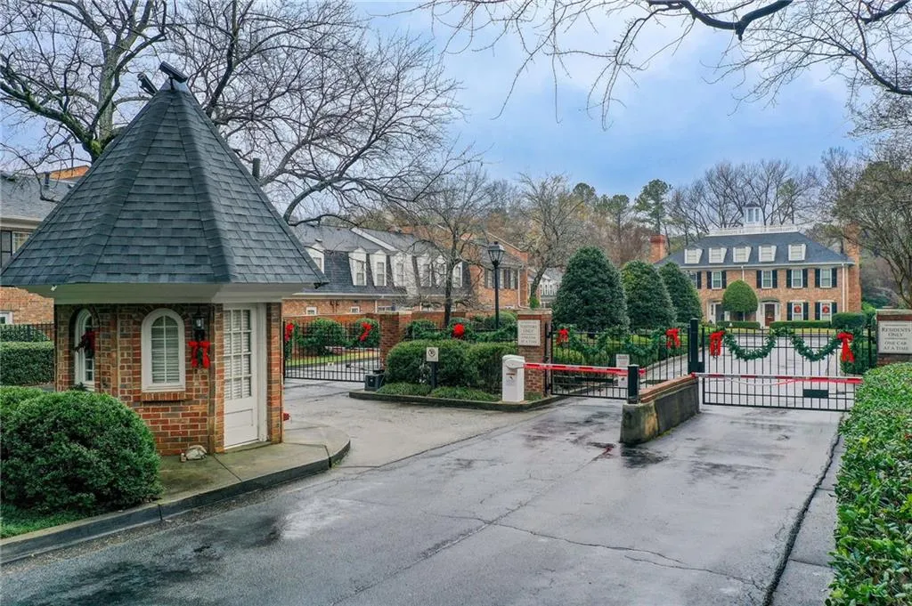 View of asphalt road with a gate, a gated entry, curbs, and street lighting
