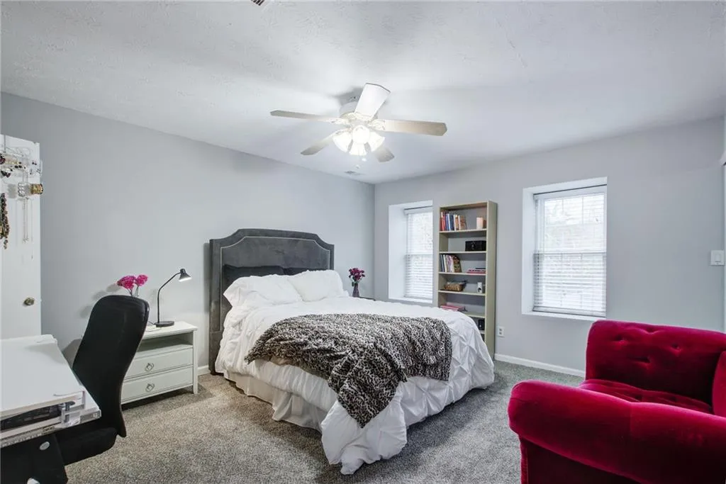 Carpeted bedroom featuring a ceiling fan and a desk