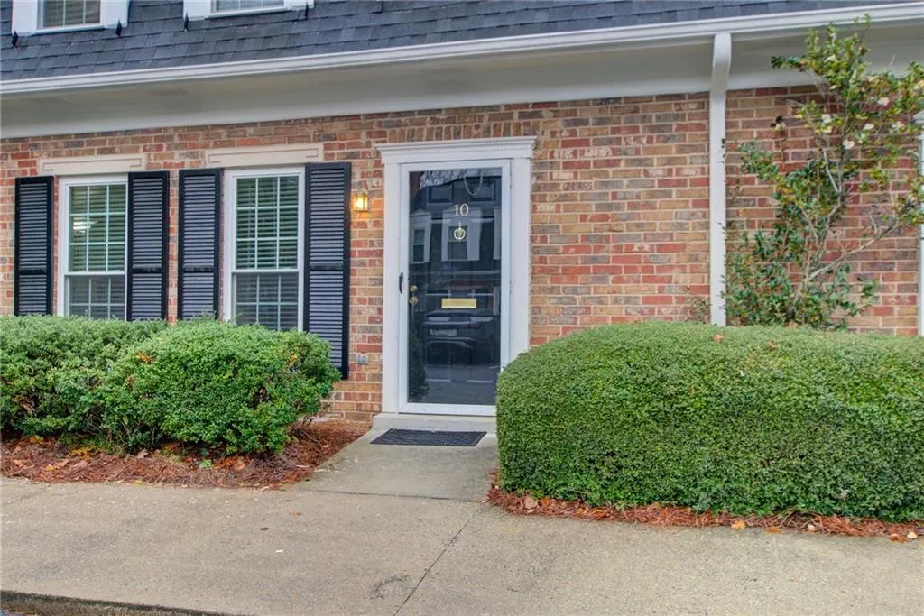 Doorway to property featuring brick siding and a shingled roof