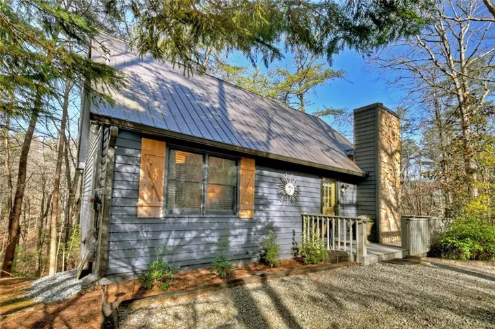 View of front of property featuring a metal roof, a chimney, and a deck