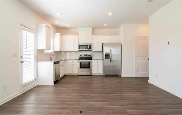 Kitchen featuring appliances with stainless steel finishes, plenty of natural light, white cabinets, and dark hardwood / wood-style floors