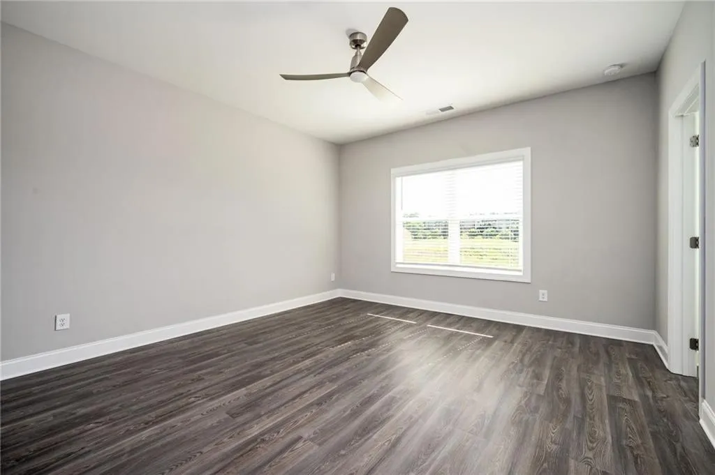 Empty room with dark wood-style floors and ceiling fan