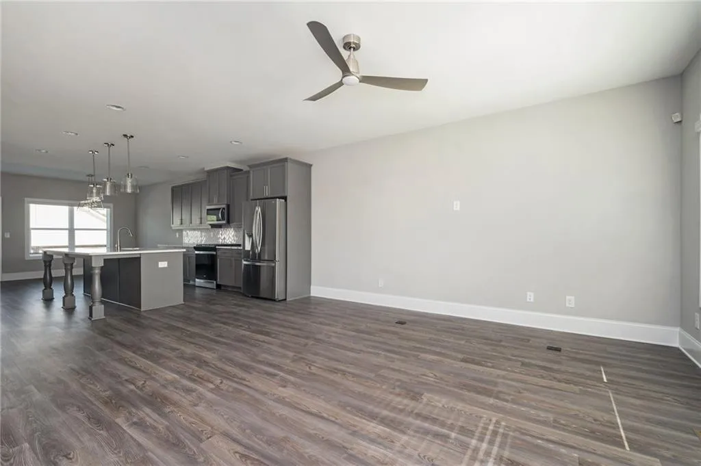 Kitchen featuring a kitchen bar, an island with sink, gray cabinetry, open floor plan, and light countertops
