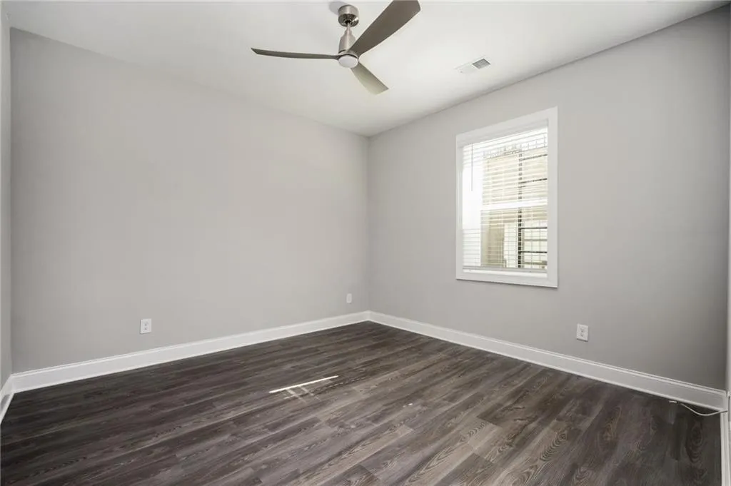 Unfurnished room with dark wood-style floors and ceiling fan