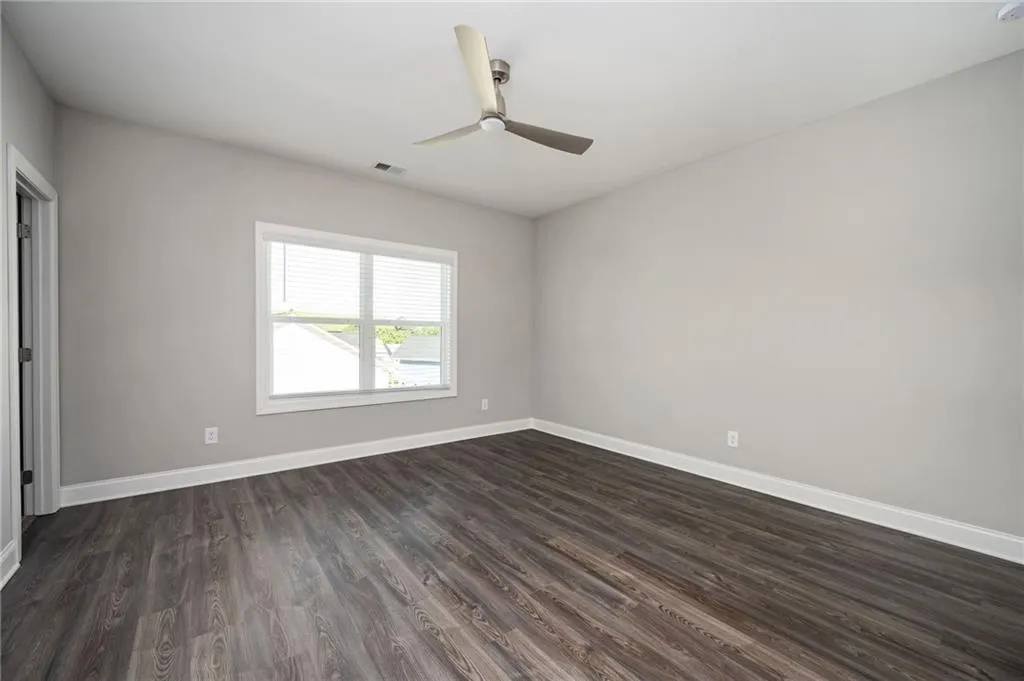 Spare room featuring dark wood-type flooring and ceiling fan