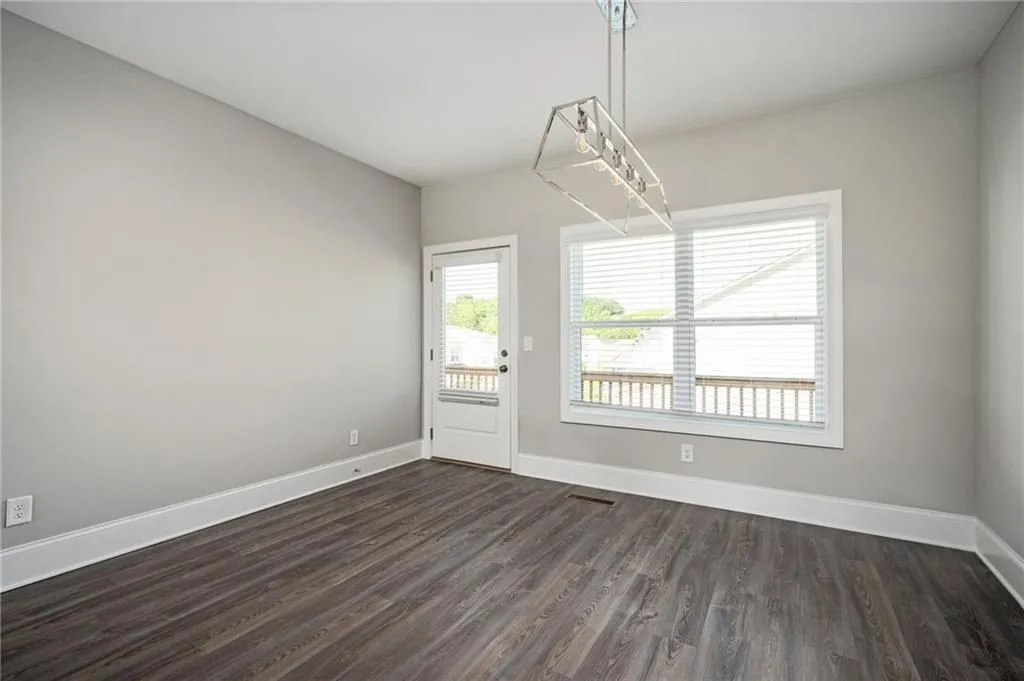 Unfurnished dining area with dark wood-style floors and baseboards