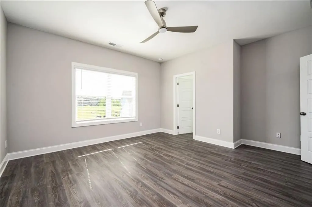 Unfurnished room featuring dark wood-style floors and a ceiling fan