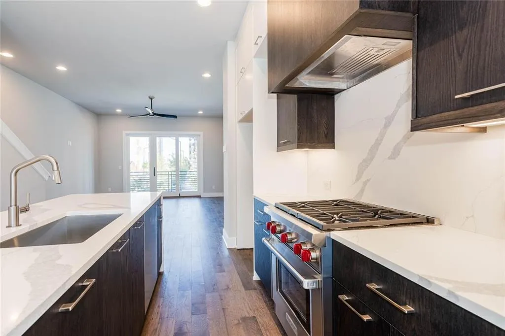 Kitchen featuring dark brown cabinetry, designer stove, ceiling fan, sink, and dark hardwood / wood-style floors