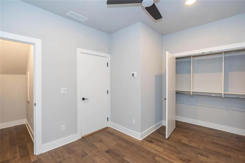 Unfurnished bedroom featuring a closet, dark wood-type flooring, and ceiling fan