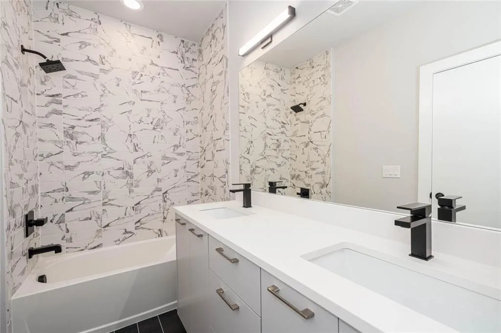 Bathroom featuring tile floors, tiled shower / bath, and dual vanity