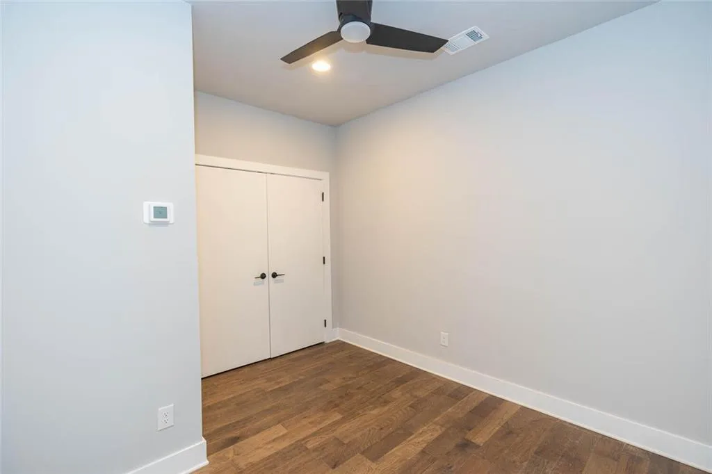 Unfurnished bedroom featuring dark hardwood / wood-style flooring, a closet, and ceiling fan
