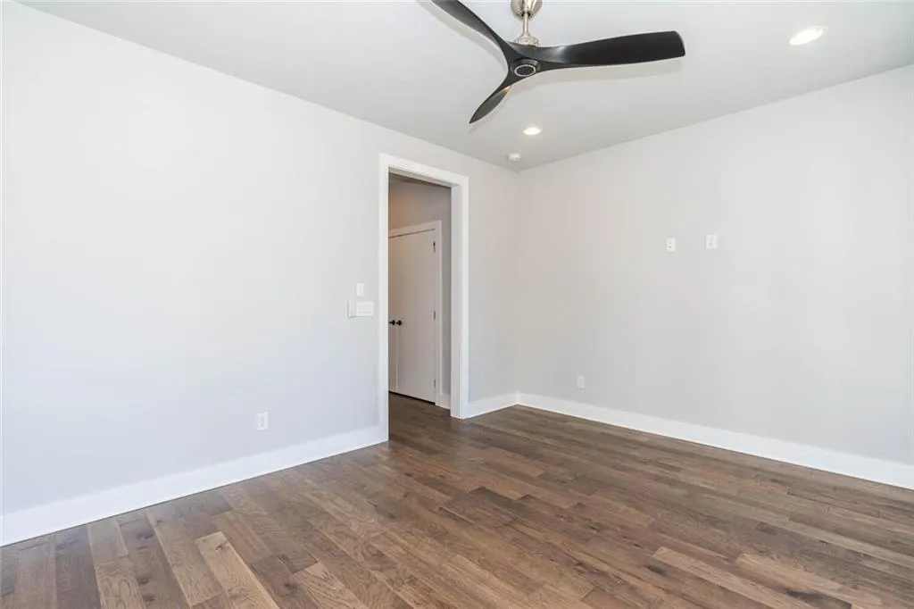Unfurnished room featuring dark wood-type flooring and ceiling fan