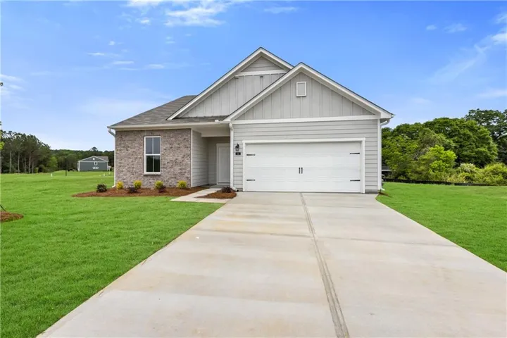 Contemporary ranch-style home featuring a two-car garage, partial brick facade, light-toned siding, and a concrete driveway