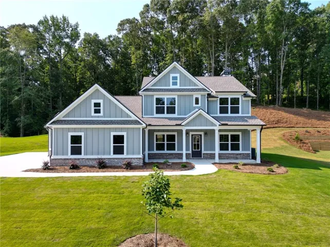 Contemporary two-story residence with a covered front porch, light gray siding, a stone foundation, and a dark asphalt shingle roof