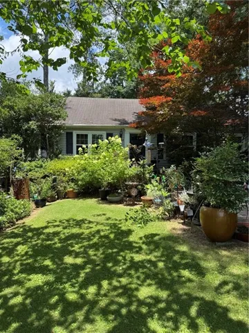 Lush backyard oasis featuring a manicured lawn, mature tree canopy providing dappled shade, and substantial landscaping with established plantings