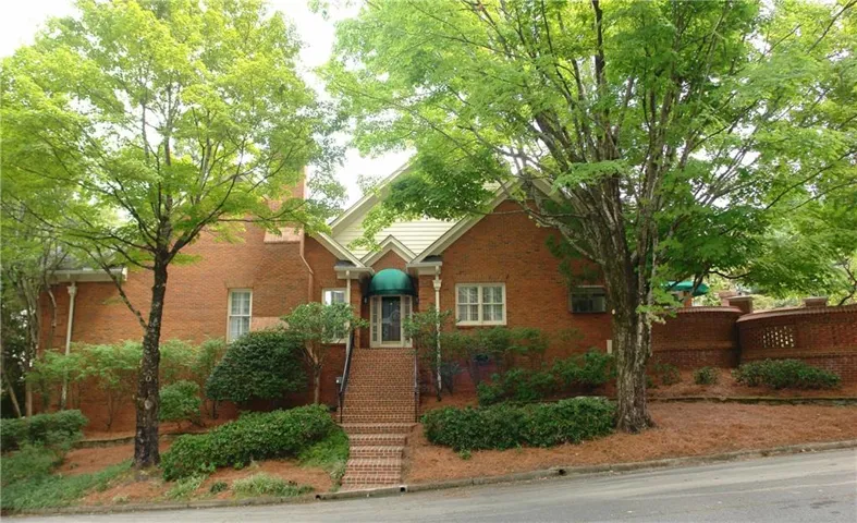 Front facade - brick exterior with a gabled roofline, front entry awning, brick steps, and mature trees