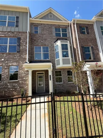 Three-story townhome featuring a brick facade with shuttered windows