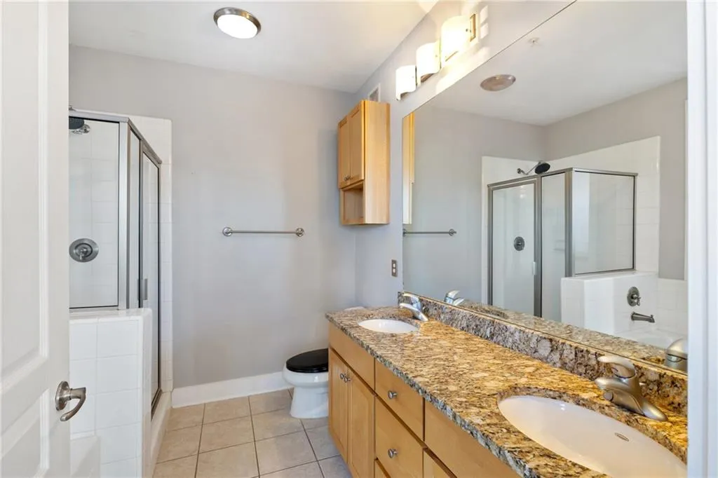 Full bath with a stall shower, tile patterned flooring, a sink, and toilet