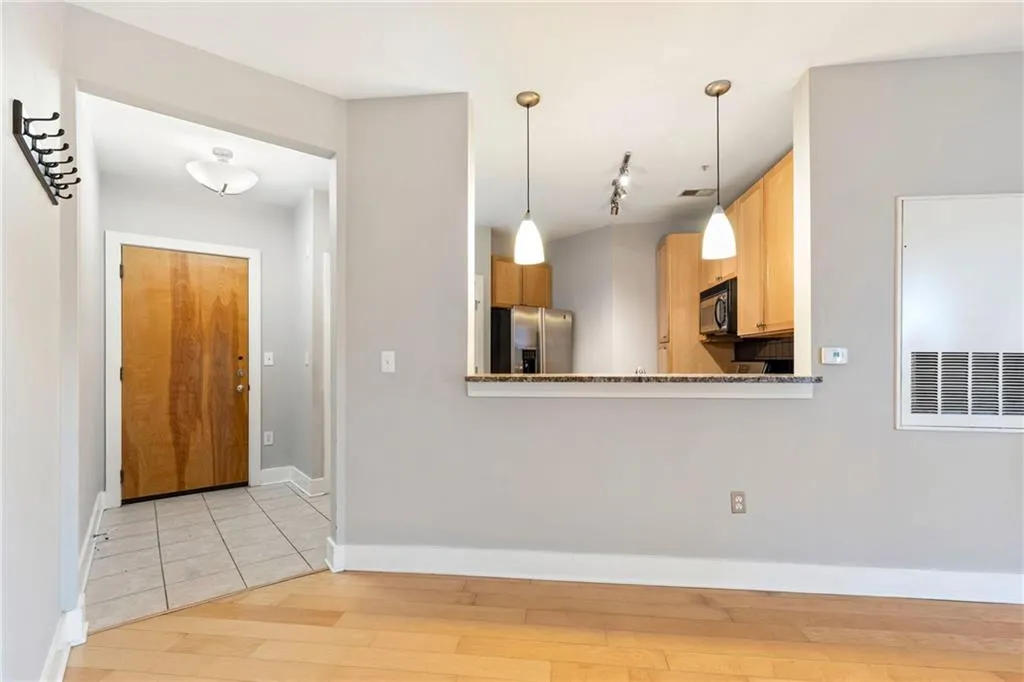 Kitchen with baseboards, stainless steel fridge with ice dispenser, light wood-style floors, black microwave, and pendant lighting